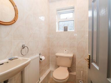 A small bathroom with a toilet sink a circular mirror a radiator and a frosted window at White Gables in Horning