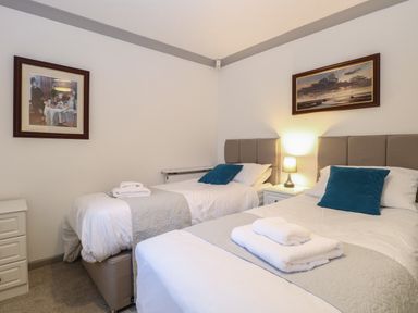 A bedroom with two single beds with white bedding and blue cushions at White Gables in Horning