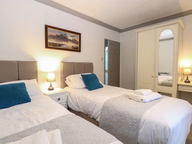 A bedroom with two single beds bedside tables lamps and a wardrobe with a mirror at White Gables in Horning
