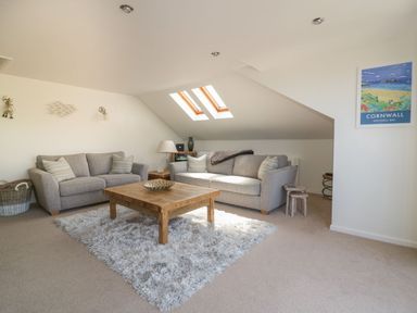 A living room with two sofas a wooden coffee table and skylight windows at Atlantic View in Holywell Bay