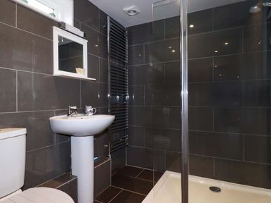 A bathroom with a toilet pedestal sink mirror shower and towel radiator at Crab Cottage Delabole