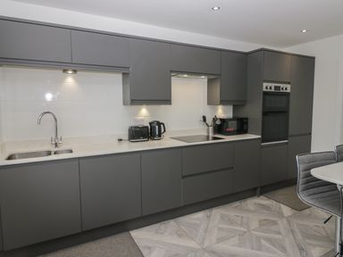 A kitchen with gray cabinets a sink a toaster kettle microwave and an oven at Edgemere Cottage in Cartmel