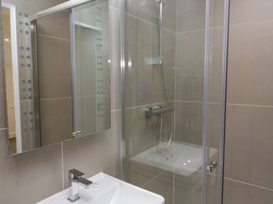 A bathroom with a sink a faucet a mirrored cabinet and a glass shower enclosure at Edgemere Retreat in Cartmel