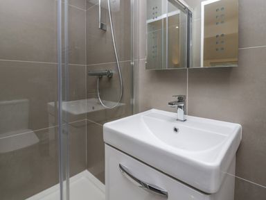 A bathroom with a shower enclosure a sink with a faucet and a mirror cabinet at Edgemere Retreat in Cartmel