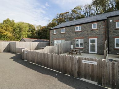 A stone building with wooden fenced patios and picnic tables at Edgemere Retreat in Cartmel