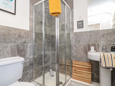 A bathroom with a shower enclosure a toilet and a pedestal sink at Coastal Retreat in Seahouses