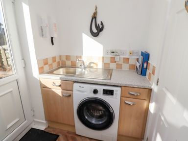 A laundry room with a washing machine sink and countertop at Coastal Retreat in Seahouses