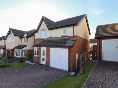 A residential street with two-story houses featuring garages and driveways at Coastal Retreat in Seahouses
