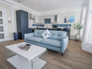 A living room with a blue sofa and coffee table at Vista Mare 1 in Weymouth