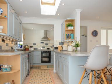 A kitchen with blue cabinets a skylight and bar stools at Seamay in Polzeath