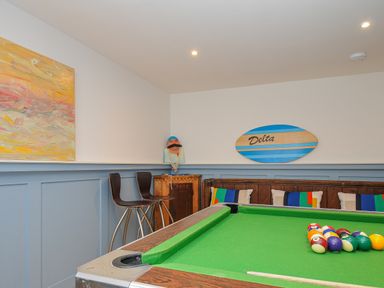 A game room with a pool table chairs and wall decor at Seamay in Polzeath