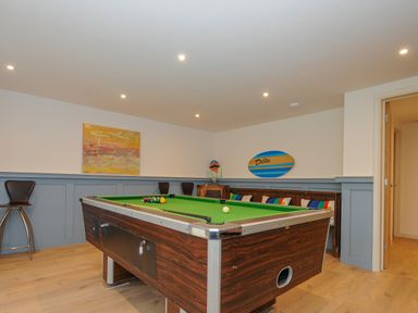 A room with a pool table stools and seating with colorful cushions at Seamay Polzeath