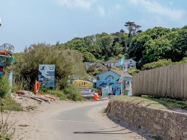 A coastal path leading to a marine centre building surrounded by trees and signage at Seamay in Polzeath