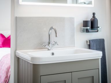 A bathroom sink with a chrome faucet a gray cabinet a black soap dispenser and a gray towel at Hoheck in Abersoch