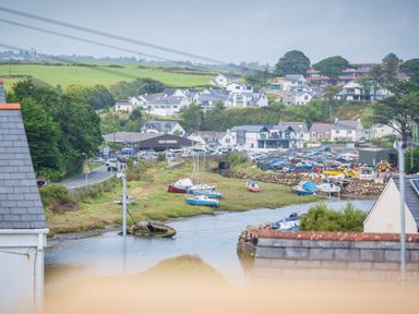A small harbor with boats on water and grassy banks surrounded by houses and buildings at Hoheck in Abersoch