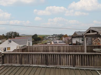 A view of rooftops and a wooden fenced balcony with a partly cloudy sky at Hoheck in Abersoch