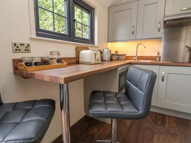 A kitchen with a wooden countertop stools jars toaster kettle and a sink at The Retreat in Bangor-On-Dee