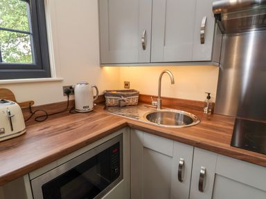 A kitchen corner with a microwave oven a toaster a kettle a sink and cabinets at The Retreat in Bangor-On-Dee