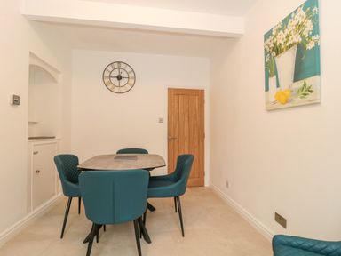 A dining area with four blue chairs around a table and a painting on the wall at 4 Noel Court in Chipping Campden