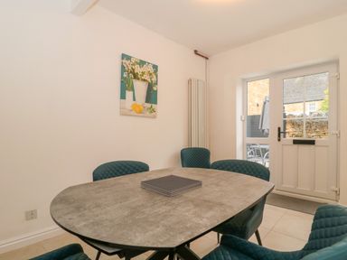 A dining room with a table and four chairs near a glass door at 4 Noel Court in Chipping Campden