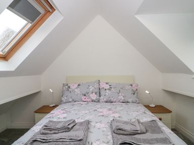 A bedroom with a bed with floral bedding and two bedside tables with lamps at 4 Noel Court in Chipping Campden