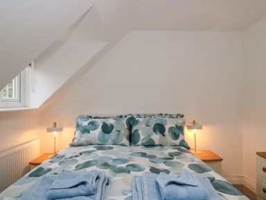A bedroom with a bed with patterned bedding and two bedside tables with lamps at 4 Noel Court in Chipping Campden