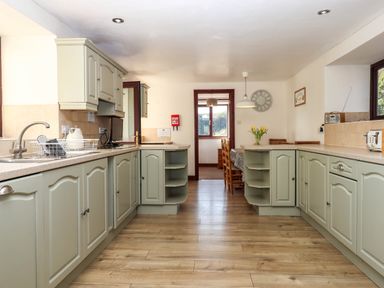 A kitchen with light green cabinets and wooden floor at Valley House in Halberton near Tiverton