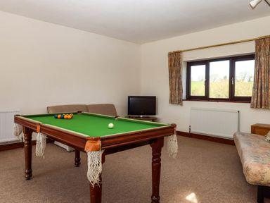 A room with a pool table a television two sofas and a window with curtains at Valley House in Halberton near Tiverton