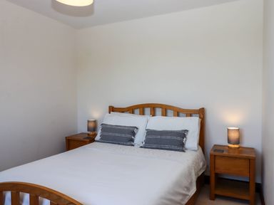 A bedroom with a wooden bed and two bedside tables each with a lamp at Valley House in Halberton near Tiverton