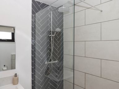 A bathroom with a shower area featuring grey herringbone tiles and white rectangular tiles at Valley House in Halberton near Tiverton