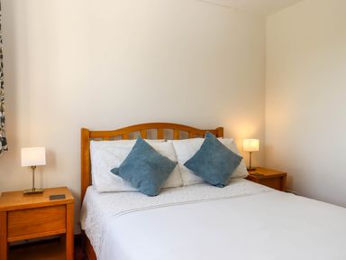 A bedroom with a wooden bed frame and two bedside tables with lamps at Valley House in Halberton near Tiverton