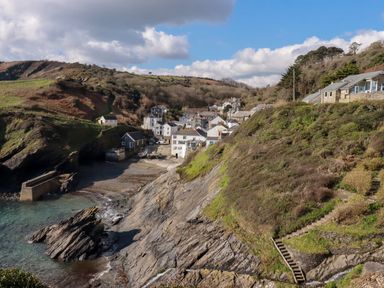 A coastal village with houses on a hillside and a rocky shoreline at Suntrap House in Portloe