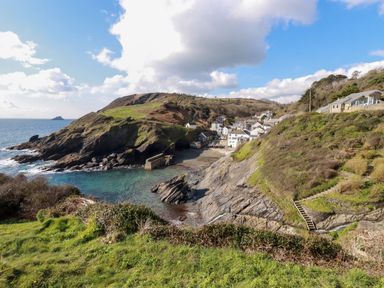 A coastal village with houses near rocky cliffs and a small beach at Suntrap House in Portloe