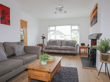 A living room with two sofas a wooden coffee table and a fireplace at Monarfon in Criccieth
