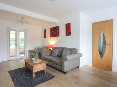 A living room with two gray sofas wooden coffee table and wooden door at Monarfon in Criccieth