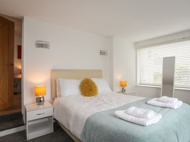A bedroom with a bed table lamps a floor mirror and towels on the bed at Monarfon in Criccieth