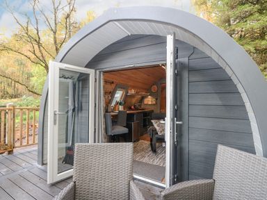 A small curved cabin entrance with open double doors showing a kitchen and seating area at Elleric Pods - The Last Resort Fasnacloich near Appin