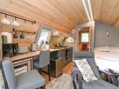 A compact living space with kitchen appliances chairs a bed and wood-paneled walls at Elleric Pods - The Last Resort in Fasnacloich near Appin