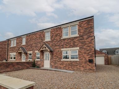 A brick exterior of a semi detached house with gravel driveway and small porch at Breamish Christon Bank near Embleton