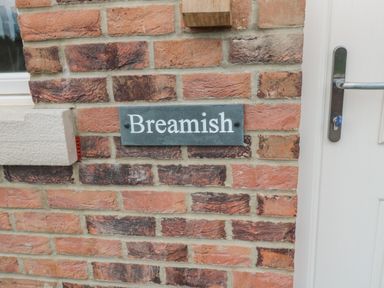 A brick wall with a nameplate reading Breamish next to a white door with a handle at Breamish in Christon Bank near Embleton