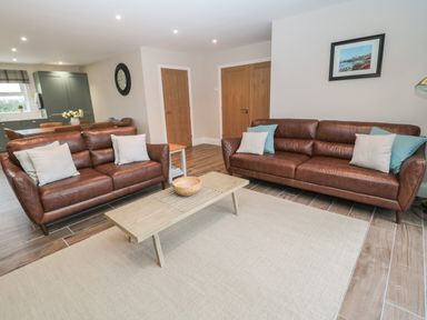 A living room with two brown leather sofas and a wooden coffee table at Breamish in Christon Bank near Embleton