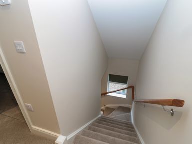 A stairway with carpeted steps and a wooden handrail leading down to a window at Breamish in Christon Bank near Embleton
