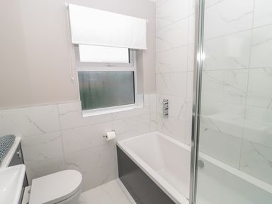 A bathroom with a bathtub shower toilet and frosted window at Breamish Christon Bank near Embleton