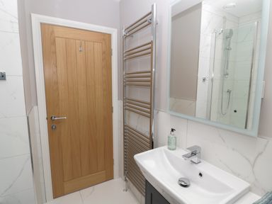 A bathroom with a wooden door a metal towel rack a sink with a faucet and a mirror above it at Breamish Christon Bank near Embleton