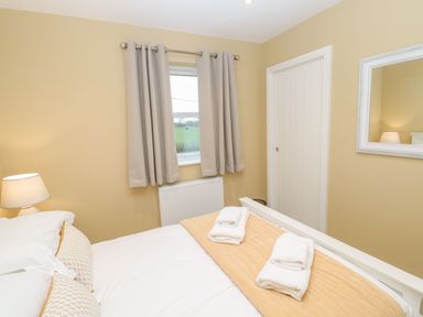 A bedroom with a bed lamp window towels on bed and a mirror on the wall at Breamish in Christon Bank near Embleton