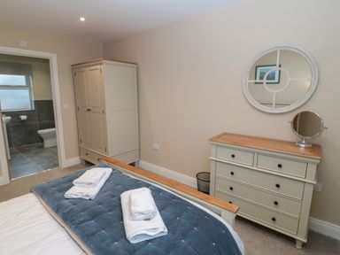 A bedroom with a bed towels on it a wardrobe and a dresser with a mirror and a small round mirror at Breamish Christon Bank near Embleton