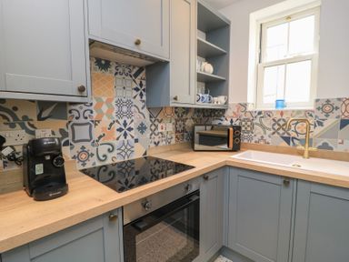 A kitchen with appliances and tiles at Weyside in Weymouth