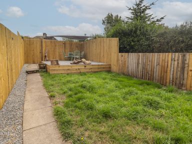 A garden with grass, a patio, chairs, and a table at 41 St. James Street Narberth