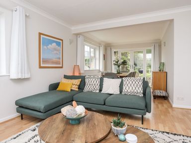 A living room with a green sectional sofa and a round wooden coffee table at The Palms in Abersoch