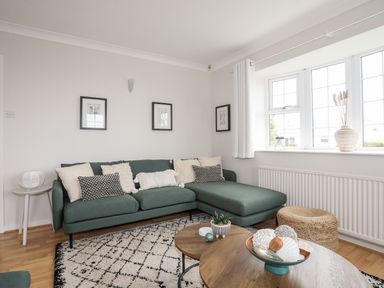 A living room with a green sofa and a round wooden coffee table by the window at The Palms in Abersoch